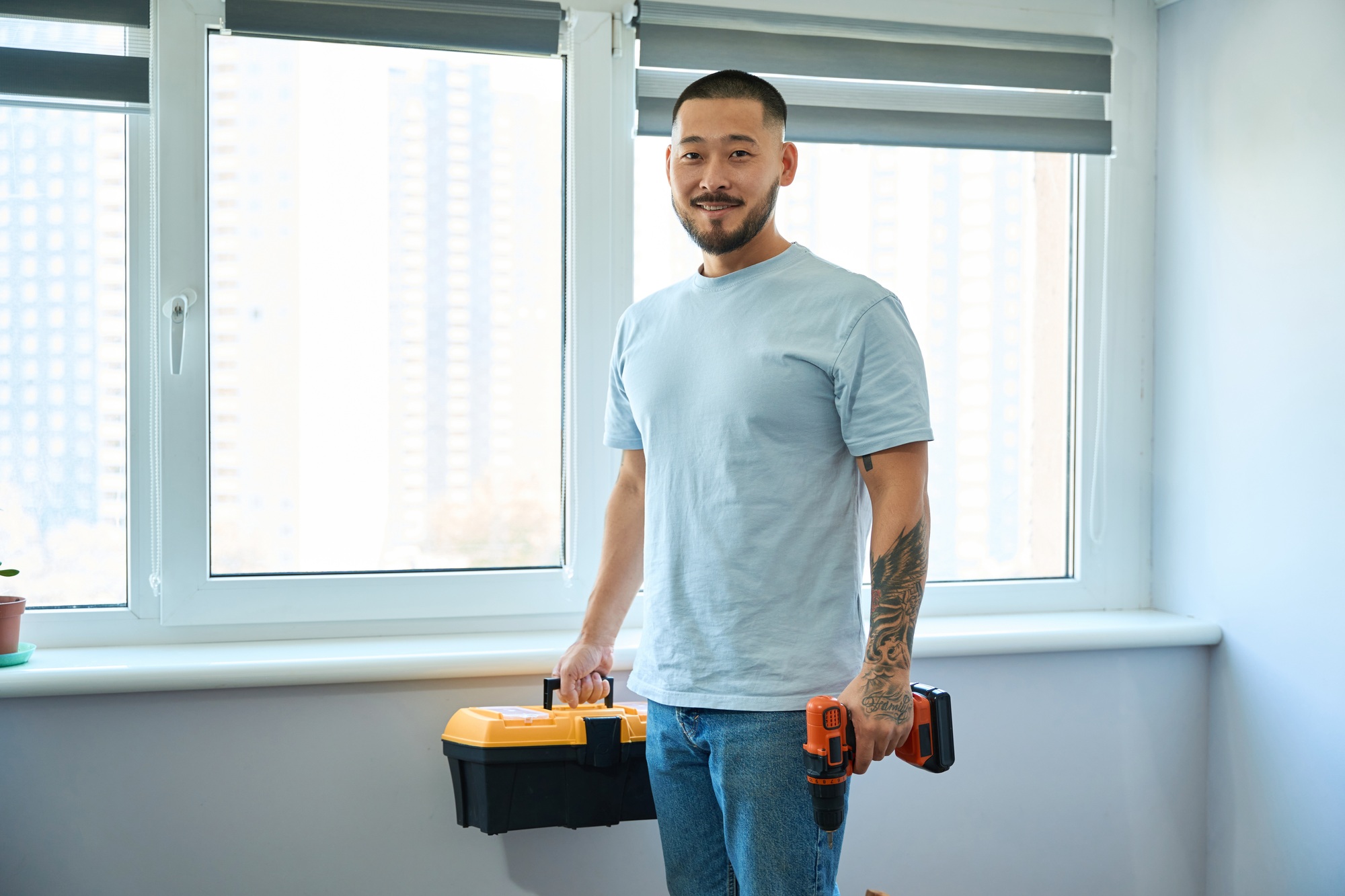 Asian man holding a toolbox and a screwdriver in his hands