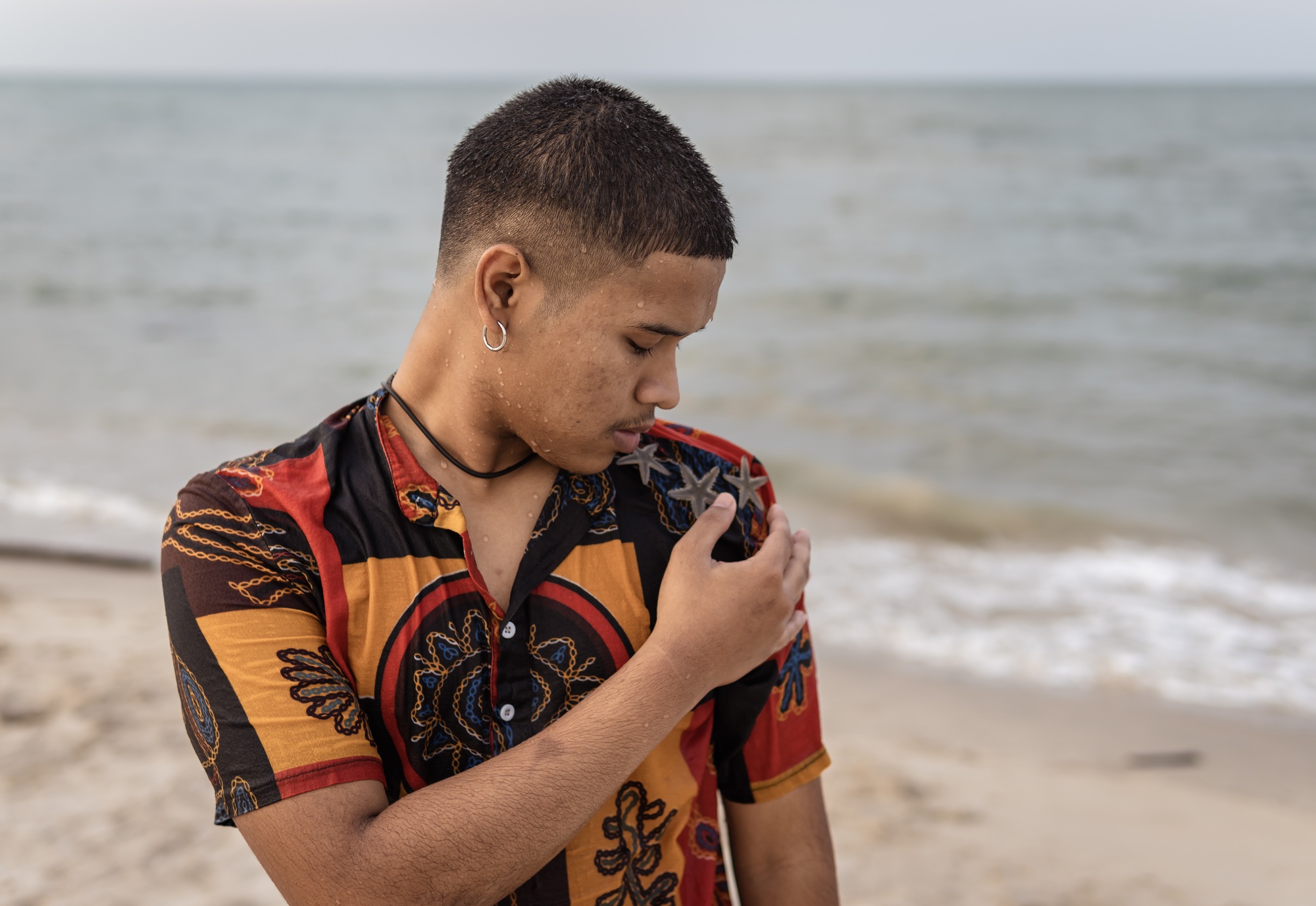 Asian men standing on the beach and watching on his shoulder with starfish