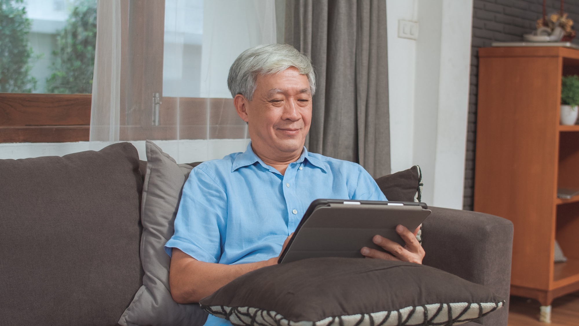 Asian senior men using tablet at home.