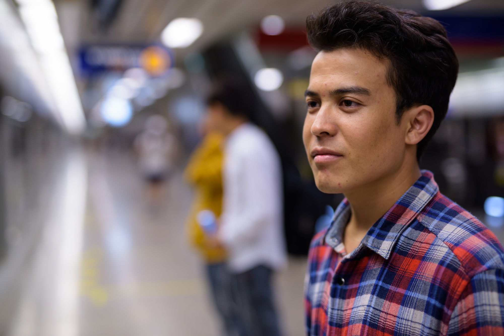Three young Asian men inside the subway train station